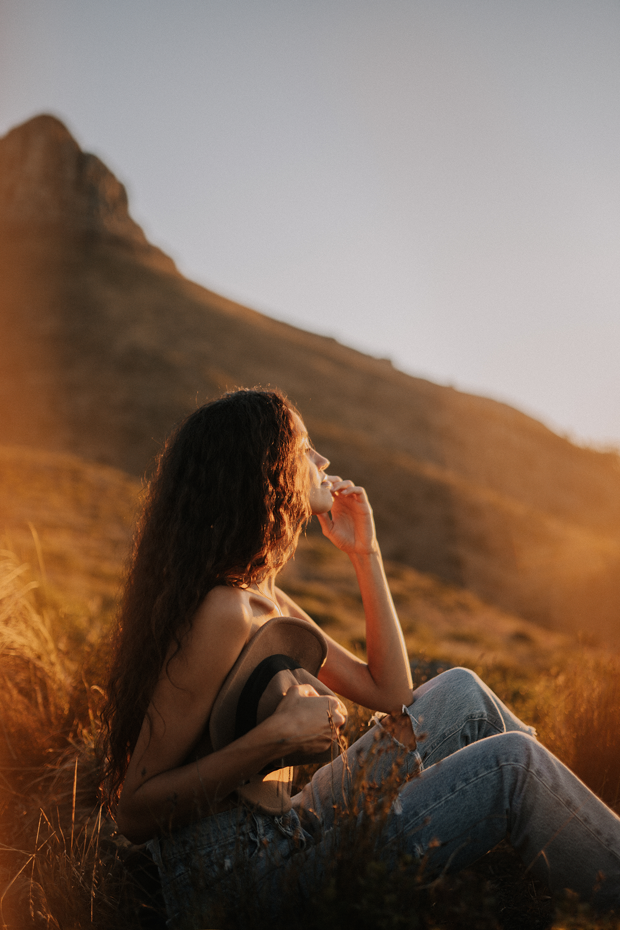 sitzende Frau im Profil vor Berg im Sonnenuntergang