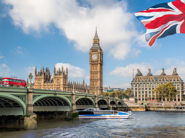 Das Bild zeigt den Big Ben, das Wahrzeichen von London, mit einer britischen Flagge